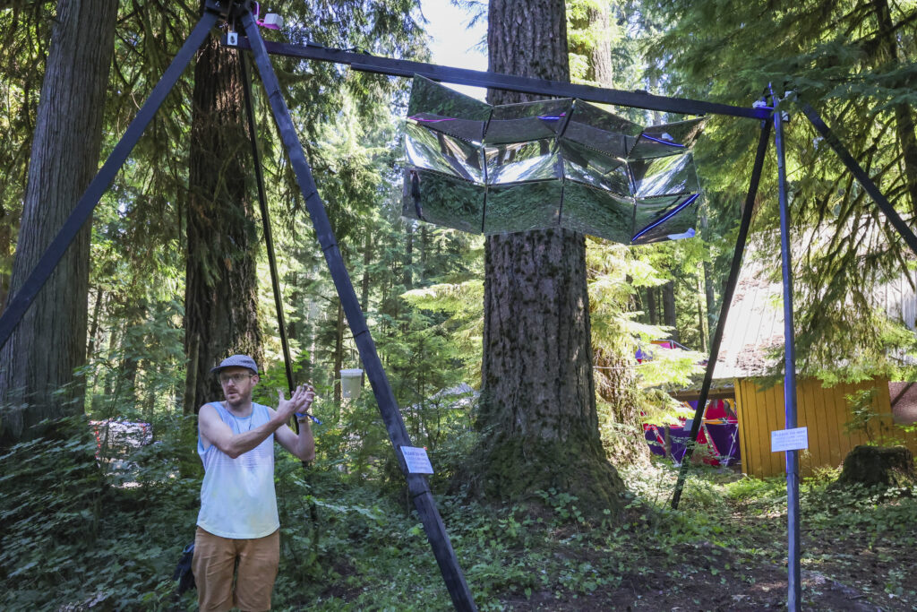 Artist Andrew Cole standing with his piece "Manifold"